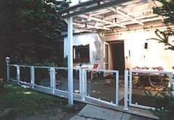 Weißer Metallzaun vor einem überdachten Patio