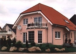 Haus mit Rosé-Fassade, Balkongeländer und Vordach