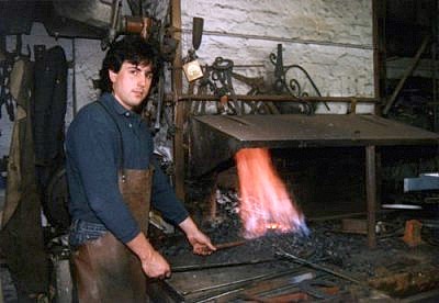 Handwerker in Lederschürze bei der Metallbearbeitung am Ofen