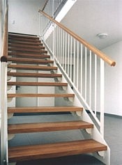Gerade Treppe mit dunklen Holzstufen und weißen Eisengeländern